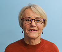 Woman wearing glasses with a blue backdrop.