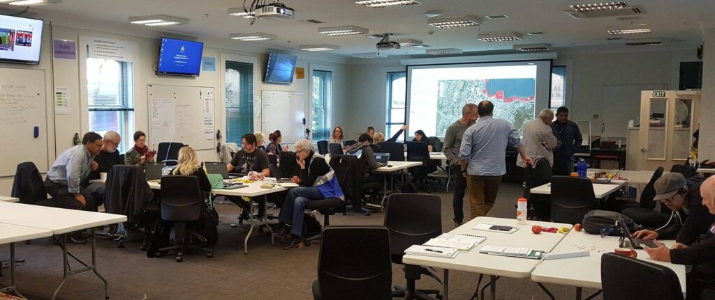 People working in an emergency operations centre with maps displayed on large screens.