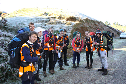 Trampers in hi-vis pose for a group photo outdoors.