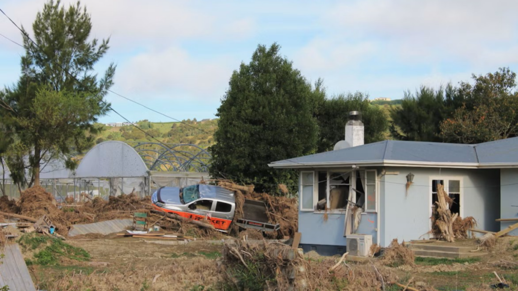 Damage to a house and vehicle following a severe weather event.