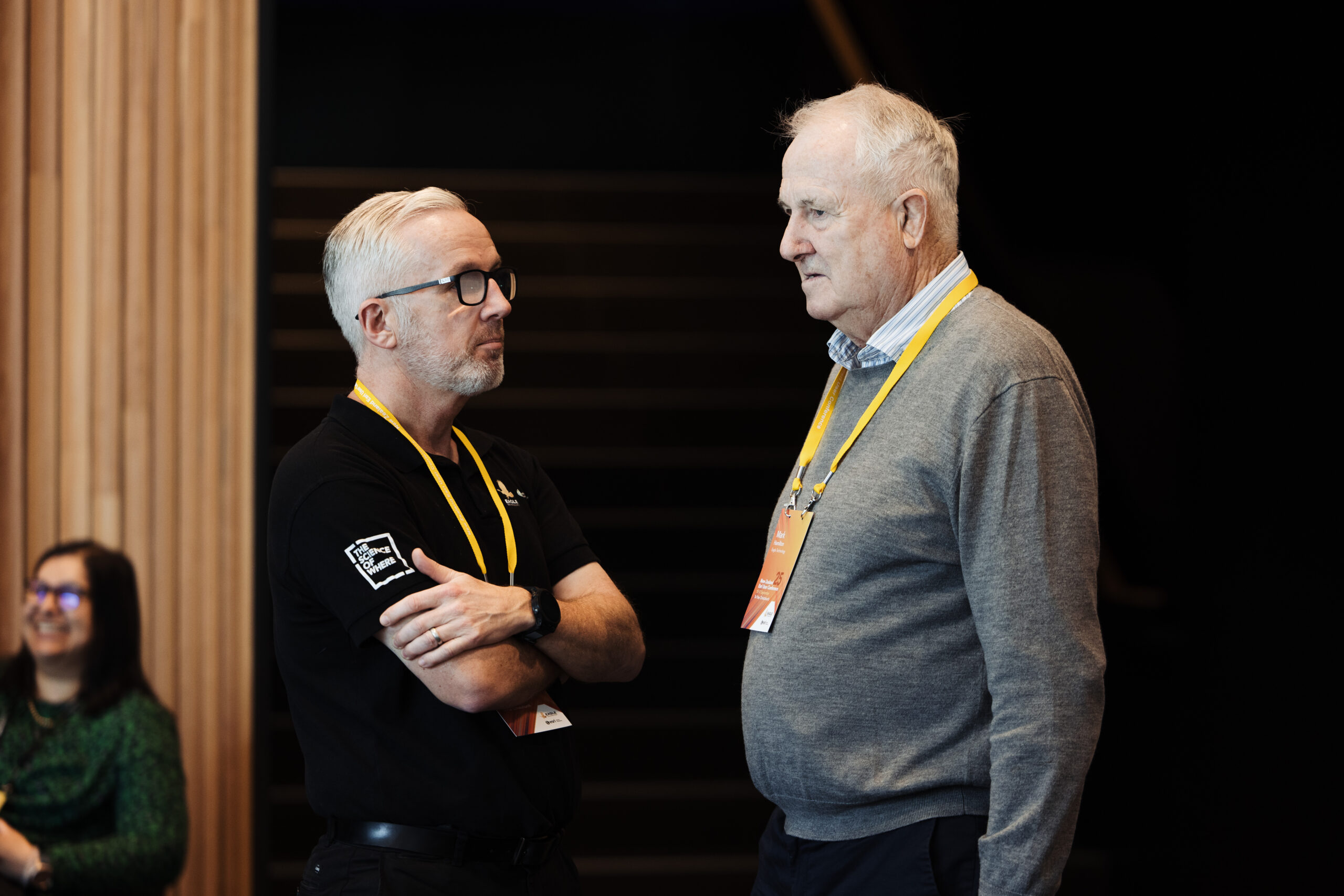 Two people wearing lanyards having a conversation in a conference venue.
