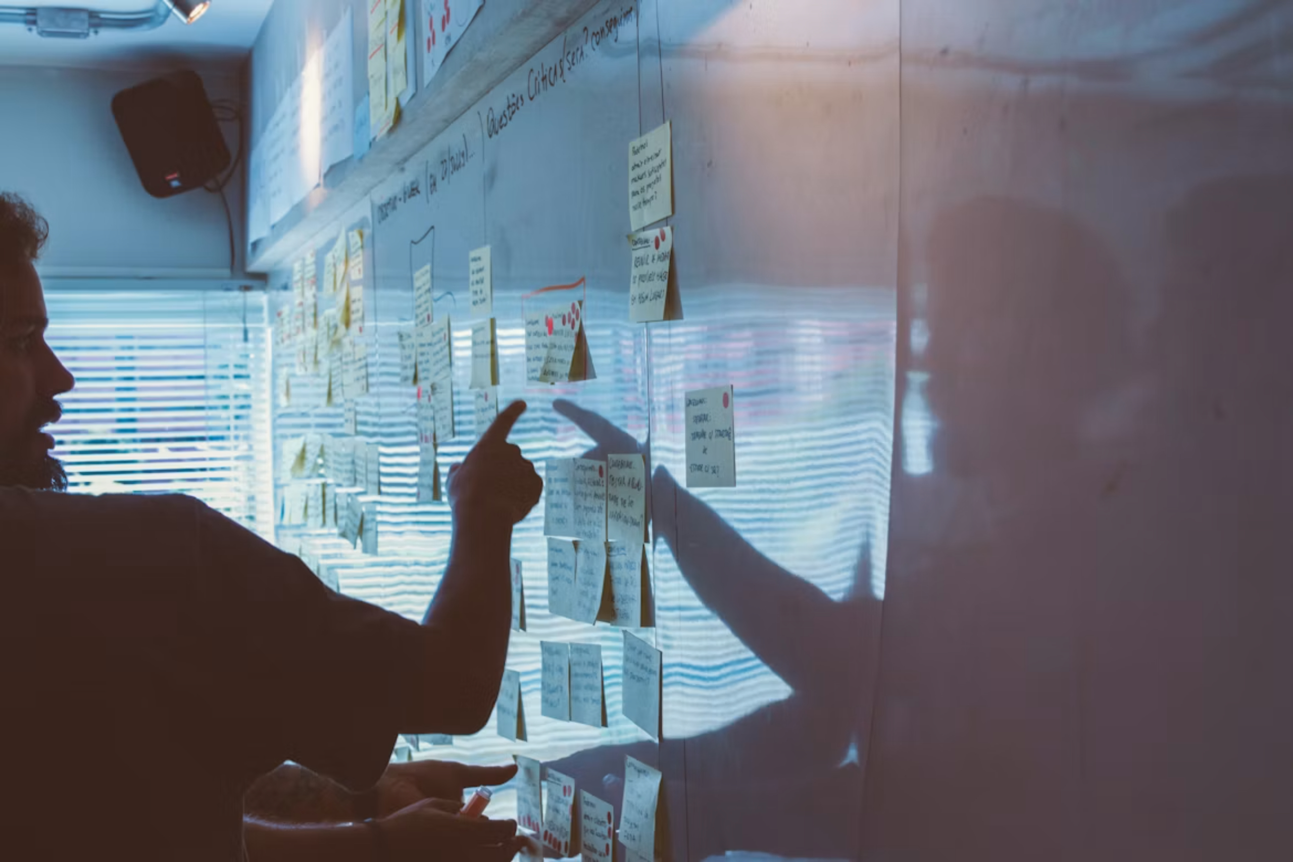 Person pointing to sticky notes on a whiteboard.