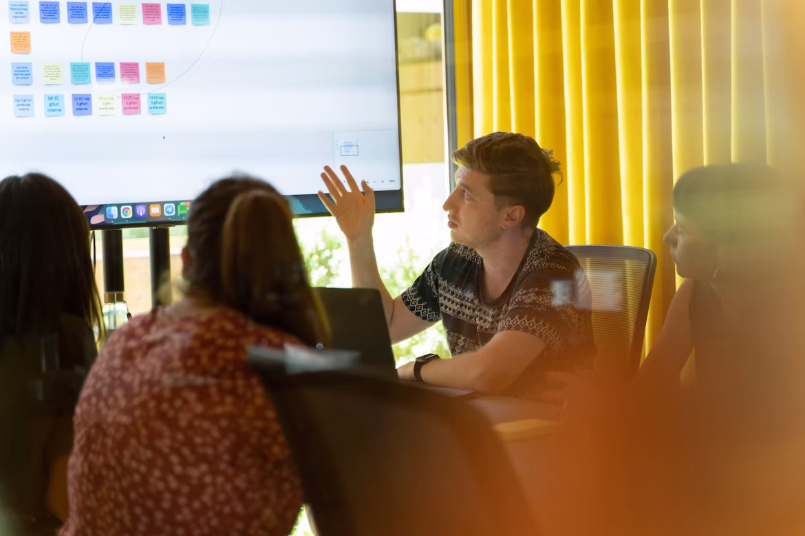 People participating in a workshop or meeting, with a presentation displayed on a screen in a conference room.