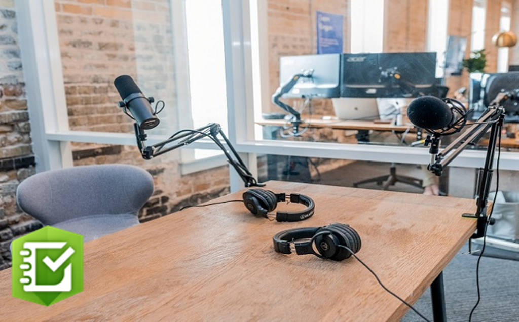 Two microphones and headphones arranged on a table in a podcast recording studio.